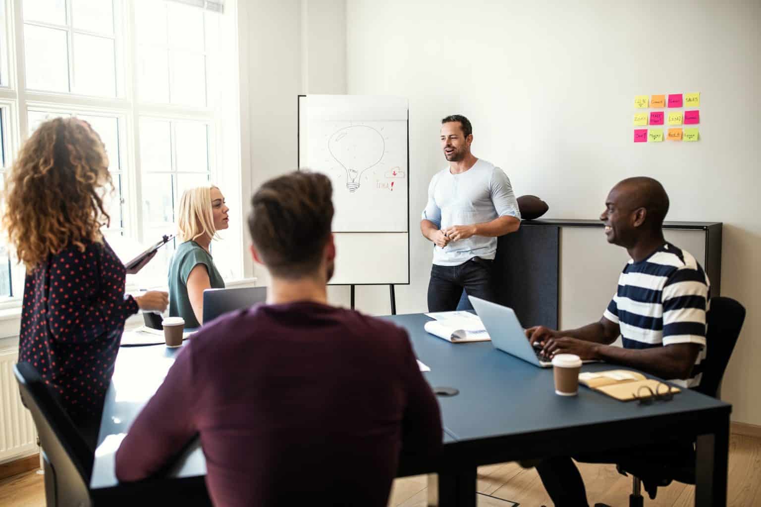 Smiling manager talking to staff during a whiteboard presentation