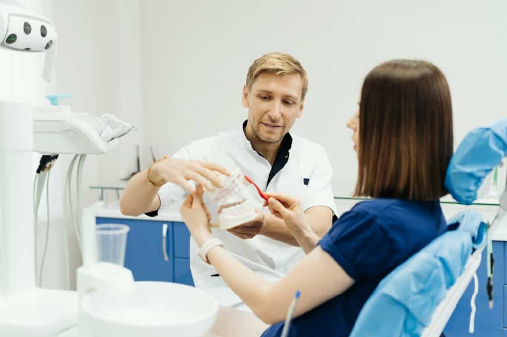 Dentist showing the correct dental hygiene on white background