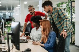 Business team of diverse professionals working together on laptops in a modern office, symbolizing collaboration, innovation, and effective tech recruitment strategies.