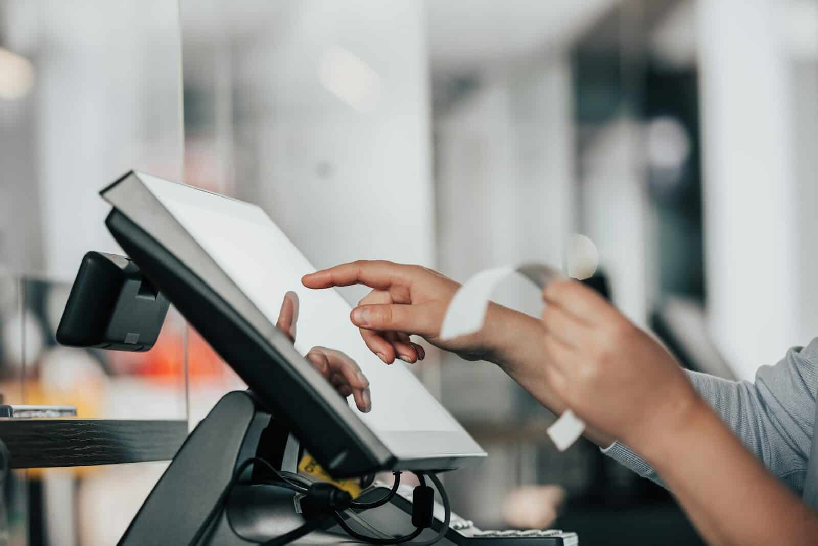 Person using a touchscreen point-of-sale device in a modern business setting.