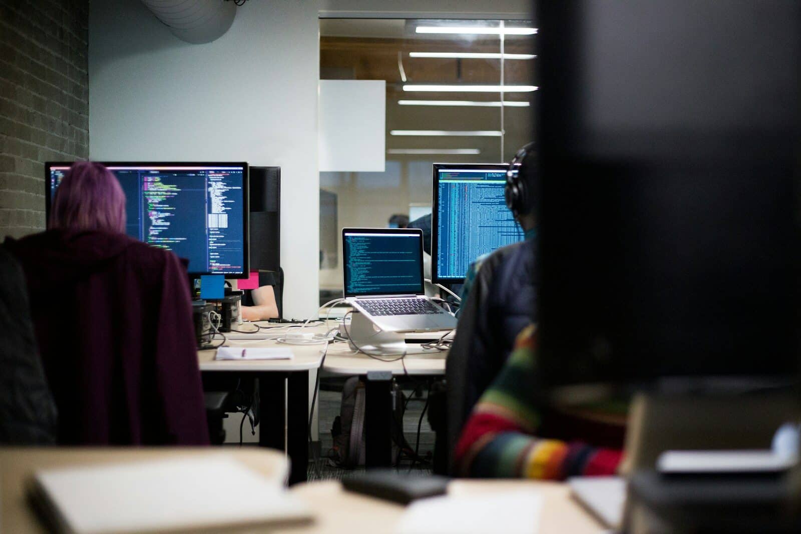 IT professionals working on multiple monitors in a modern office.