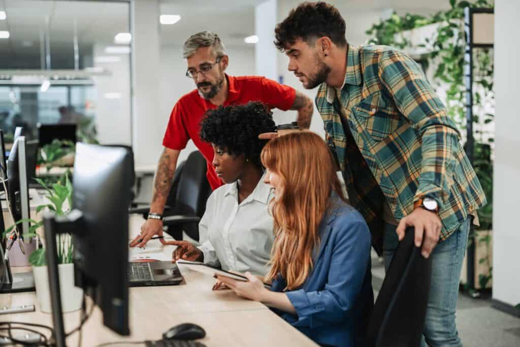 Team of diverse professionals collaborating at a computer in an office.