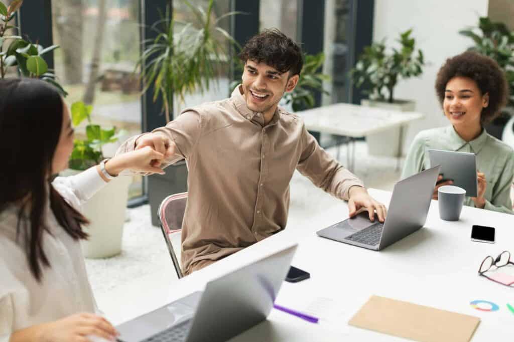 Young professionals collaborating and shaking hands in a bright office space.